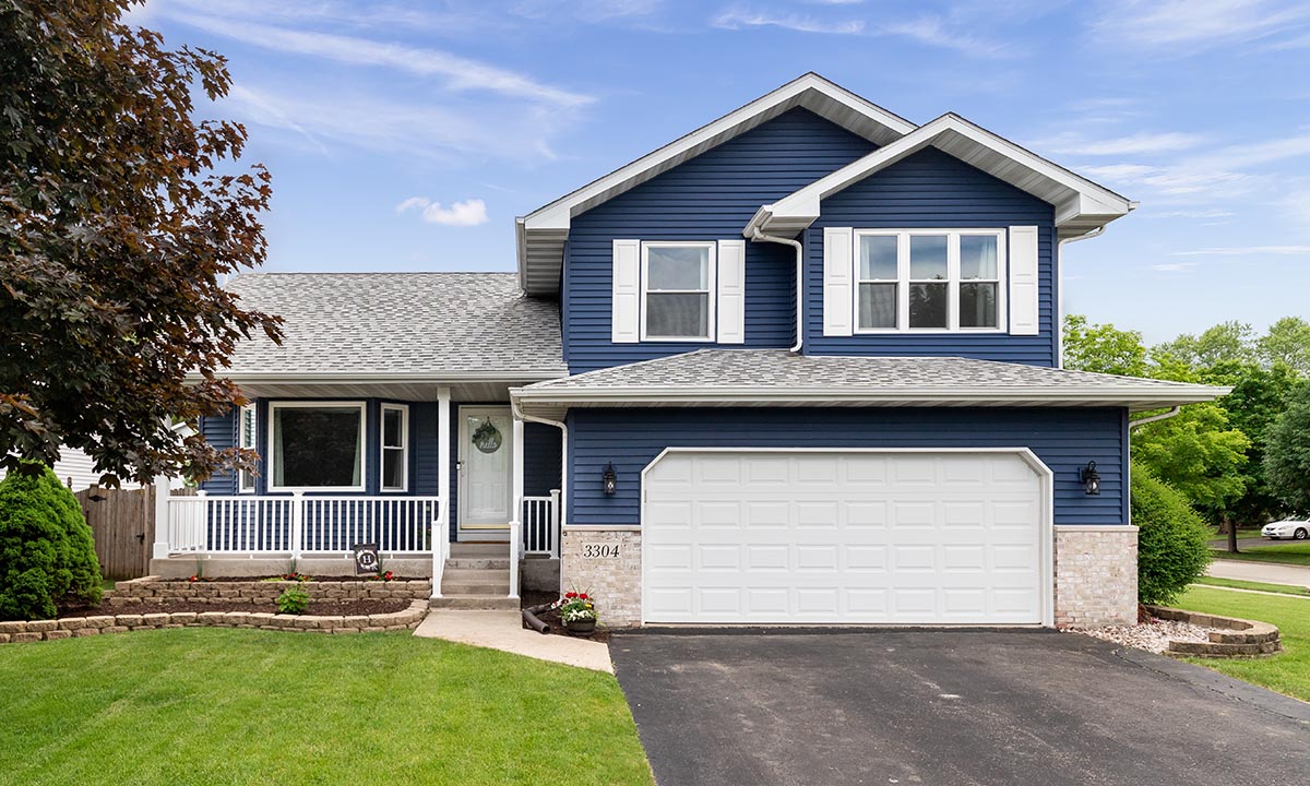 Exterior of a suburban home with blue siding, a white front porc