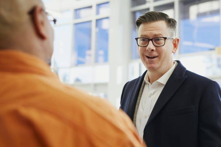 Man in suit speaking with other man