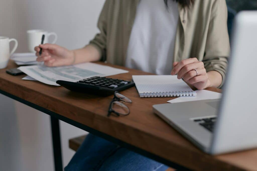 Glasses, calculator and papers on wooden table